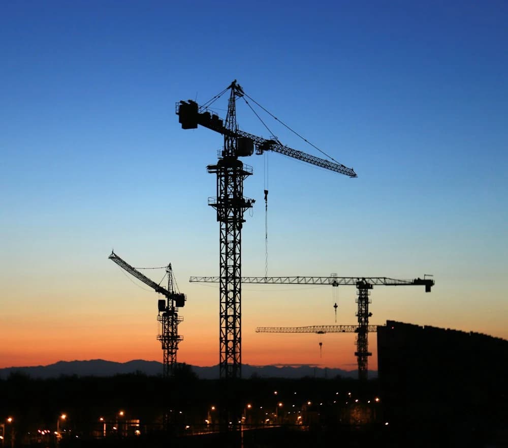 Tower cranes over a construction site at dusk