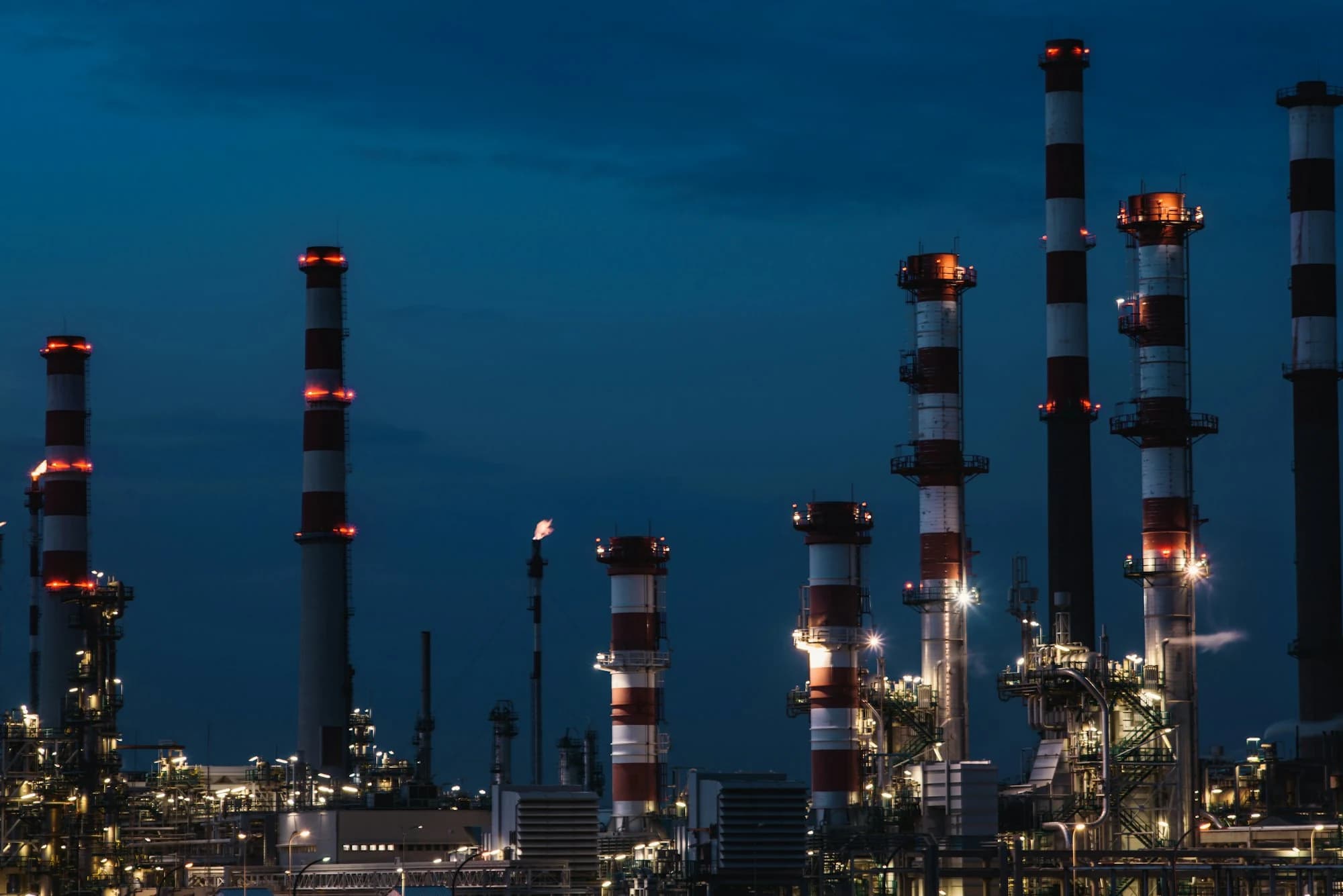 Refinery chimneys lit at dusk